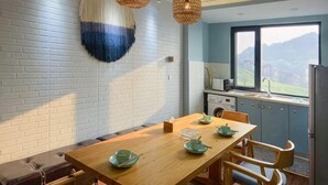 A dining area with a wooden table, chairs, and a view of the kitchen. - Black Valley Purple Rose Inn (Chongqing)