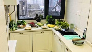 A kitchen with a window view, a sink, and various vegetables on the counter. - Black Valley Purple Rose Inn (Chongqing)