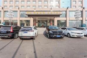 Entrada de un hotel con un cartel que dice 'VI YUAN HOTEL' y un estacionamiento con varios coches.