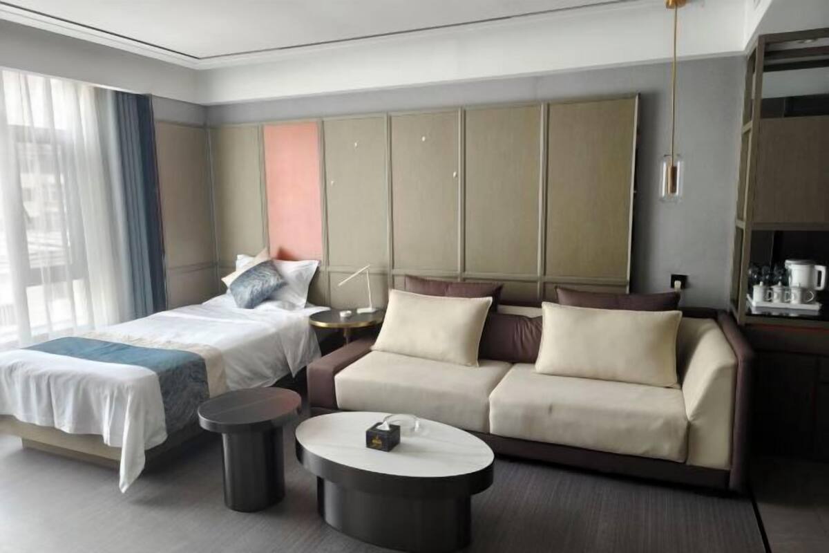 Una habitación de hotel con cama, sofá, una mesita redonda y un armario.