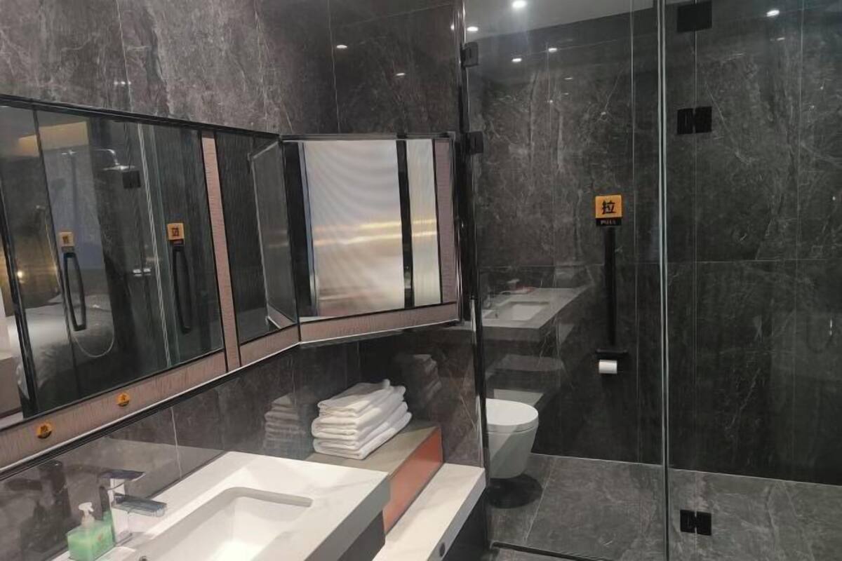 Un baño moderno con ducha de vidrio, lavamanos con espejo y retrete.