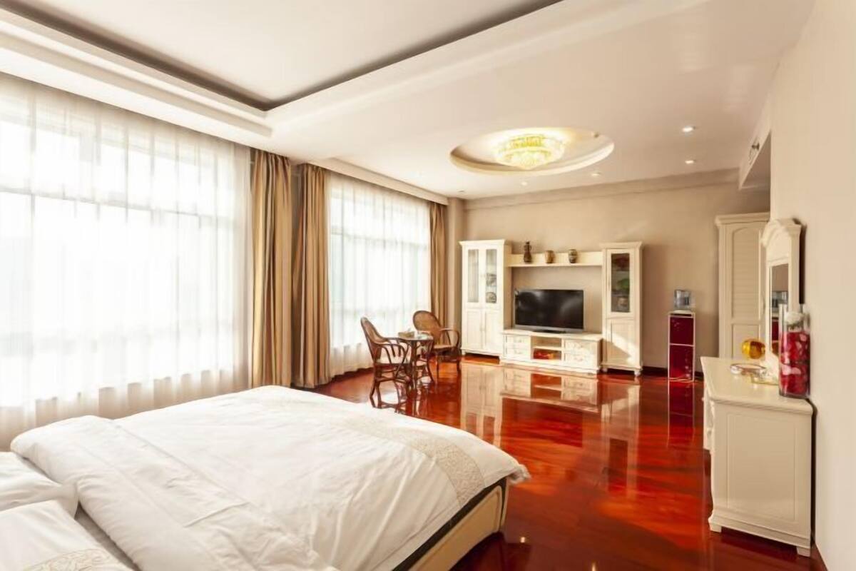 Una habitación de hotel con una cama grande, un televisor, un comedor y un espejo.