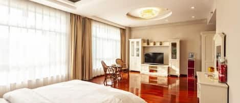 A hotel room with a large bed, a TV, a dining area, and a mirror.