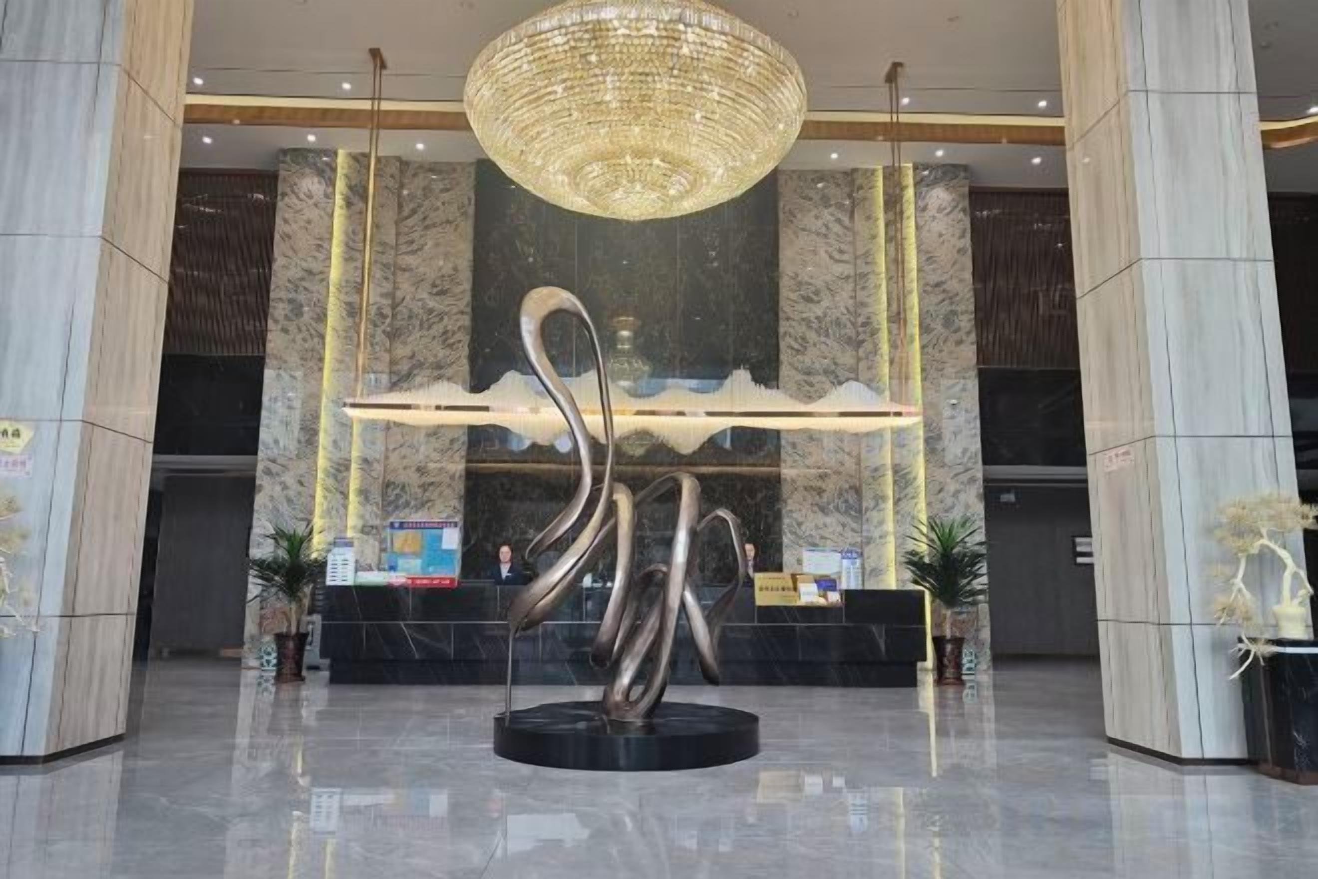 A lobby with a modern sculpture, a reception desk, and a chandelier.