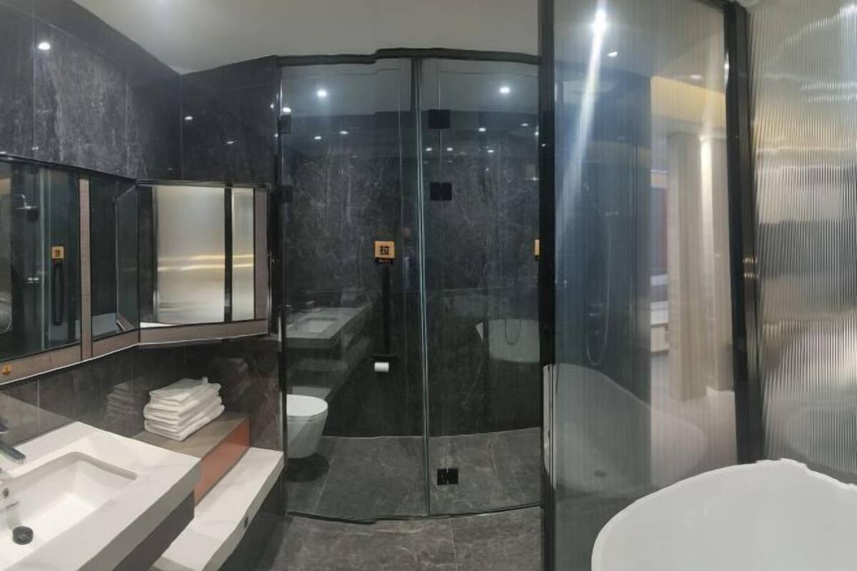 Un baño moderno con ducha envuelta en vidrio, un lavamanos blanco y un espejo.