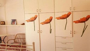 Quarto com um guarda-roupa branco decorado com grandes motivos florais nas portas.