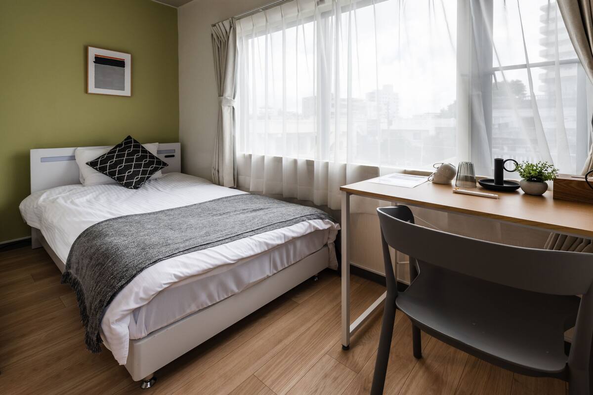 Una camera da letto ordinata con un letto, una scrivania e una sedia.