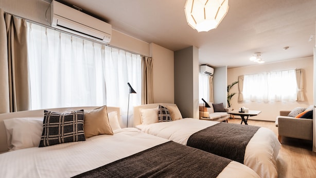 Une chambre d’hôtel avec deux lits, un canapé, une petite table et un bureau.