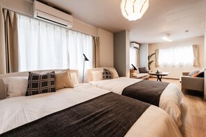 Una habitación de hotel con dos camas, un sofá, una mesita y un escritorio.