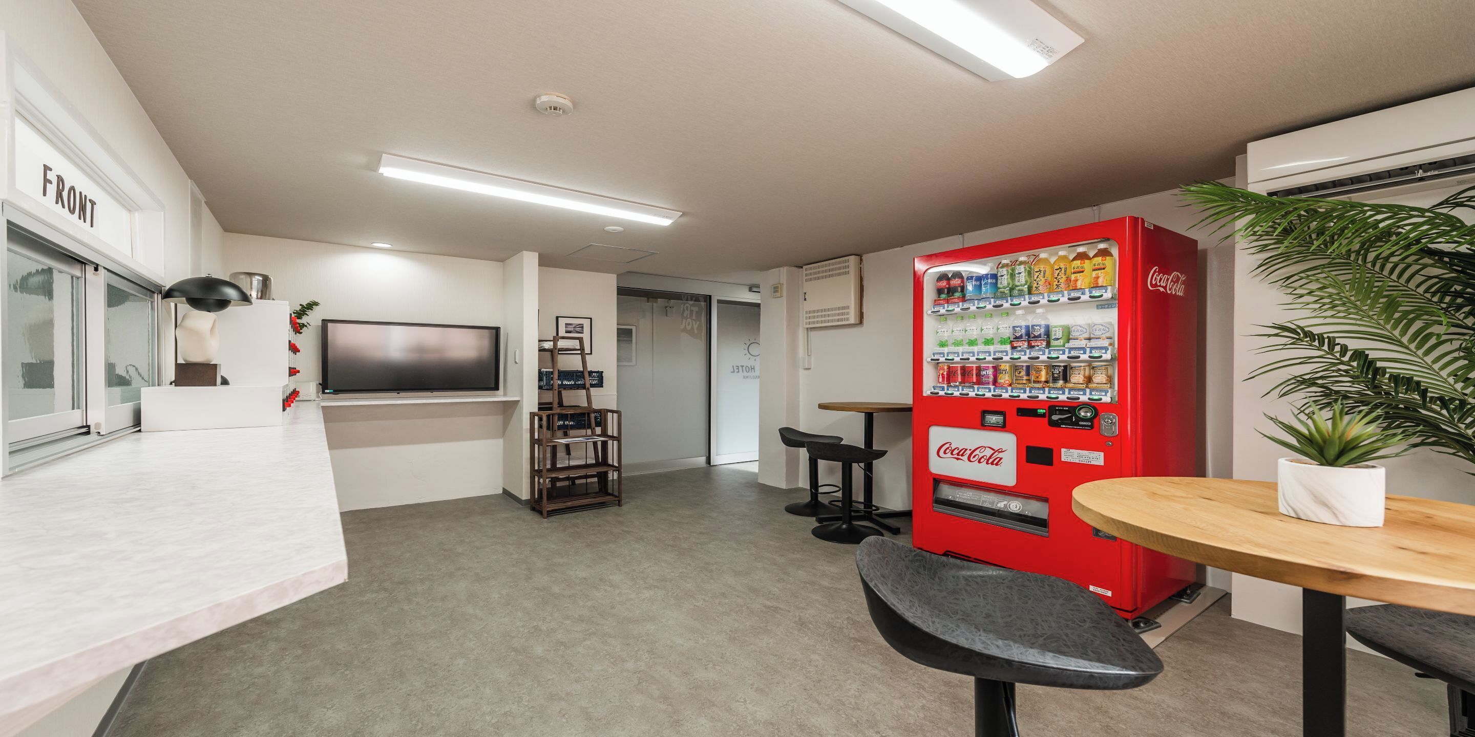 A modern office space with a red Coca-Cola vending machine, a flat-screen TV, and a minimalist design.