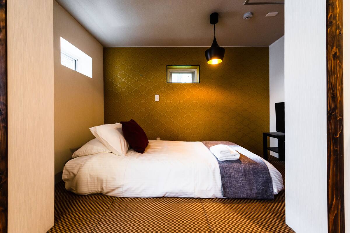 Una camera da letto con un letto, una finestra, una lampada a parete e un tavolino.
