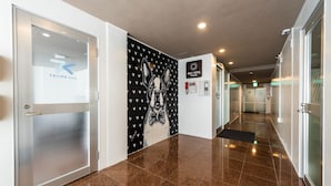 Un couloir d’hôtel avec une porte en verre sur la gauche, un mur orné d’une illustration de chien et un panneau indiquant l’hôtel Hale.