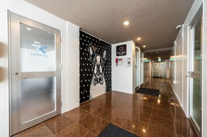 Un couloir d’hôtel avec une porte en verre sur la gauche, un mur orné d’une illustration de chien et un panneau indiquant l’hôtel Hale.