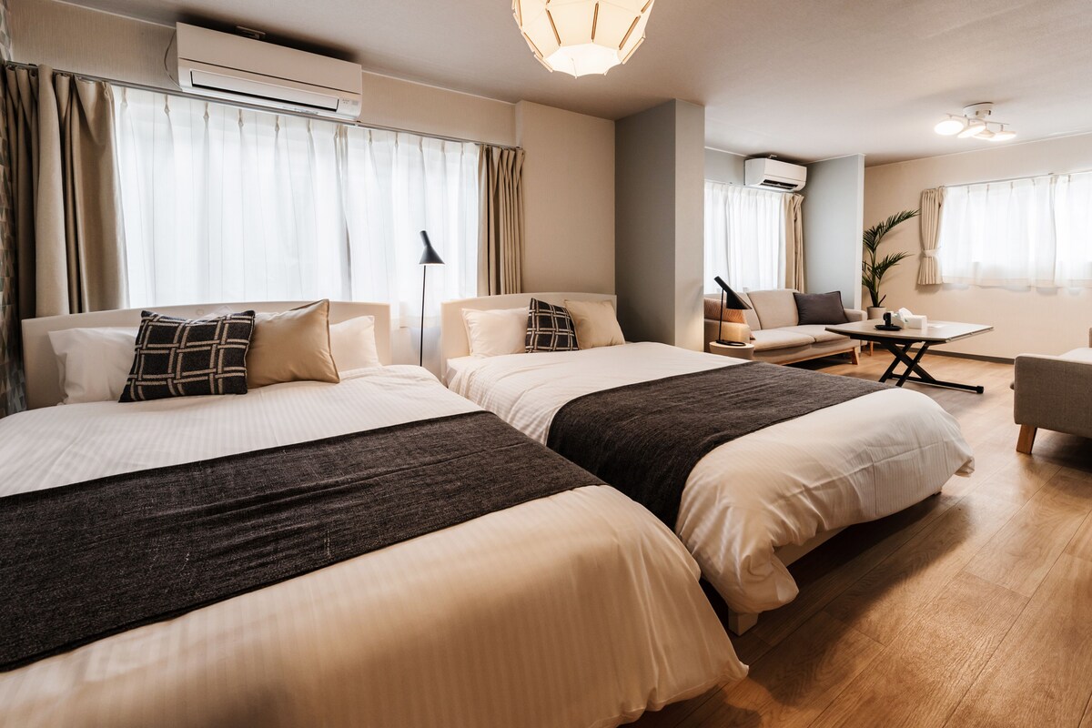 Habitación de hotel con dos camas, un sofá, una mesa y un equipo de aire acondicionado.