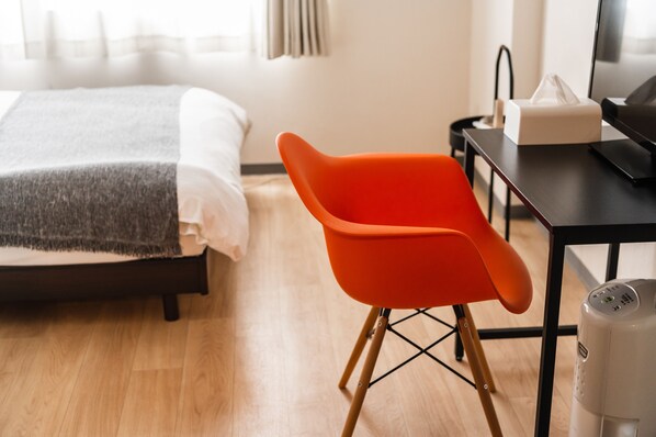Una habitación de hotel con una cama, un escritorio con una computadora, una silla y un cubo de basura.