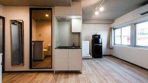 Une cuisine moderne équipée d’une cuisinière intégrée, d’un évier et d’un réfrigérateur. Une fenêtre laisse entrer la lumière naturelle et offre une vue sur l’extérieur.