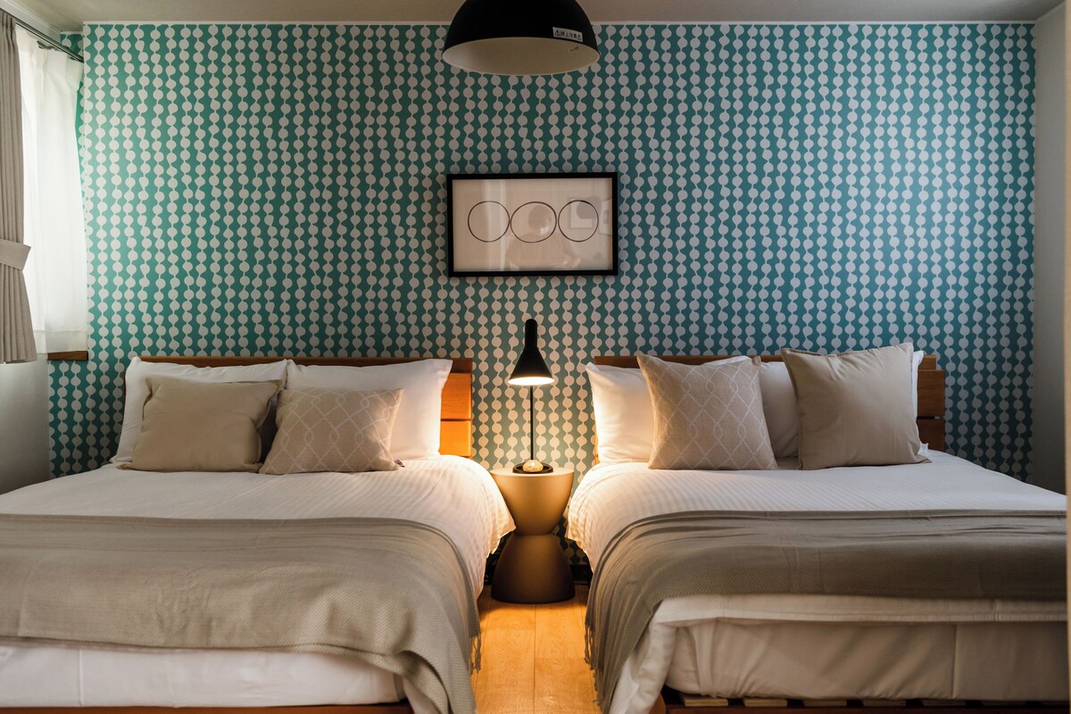 Habitación doble con dos camas, una obra de arte enmarcada en la pared y una lámpara de noche.