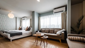 Un salon moderne avec un canapé, une petite table ronde et un lit recouvert d’une couverture.