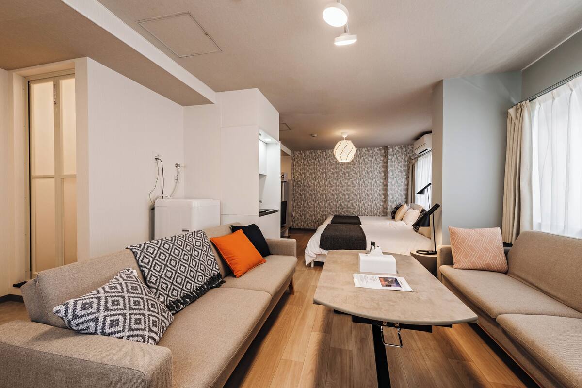 Una camera d'albergo moderna con un divano, un tavolino, un letto e un bagno sullo sfondo.