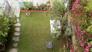 A well-maintained garden with a stone pathway, a metal table with two chairs, and various flowering plants. - Holiday Home in Greece near the Beach (Preveza)