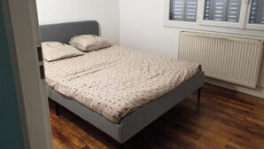 A small, single-bed room with a grey headboard, a patterned bedspread, and a window with shutters. - 3 rooms Grenoble - Saint Martin d'heres (Saint-Martin-d'Hères)