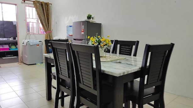 A dining area with a marble table, black chairs, a water dispenser, and a small potted plant. - OYO Homes 90567 Barakah Homestay (Tawau)