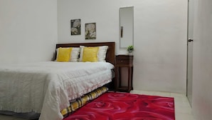 A bedroom with a bed, a nightstand, a mirror, and two wall-mounted flower paintings. - OYO Homes 90567 Barakah Homestay (Tawau)