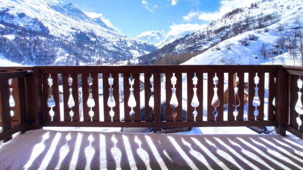 Un balcón con vistas a montañas nevadas y un cielo despejado.