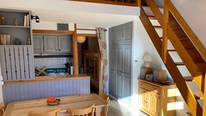 Una cocina compacta con comedor, muebles de madera y una escalera.