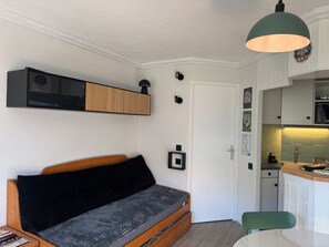 Een ruimtelijke woonruimte met een bank, een kitchenette en een eethoek.