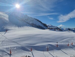 A snowy ski slope with a clear sky, ski lifts, and a mountain backdrop.