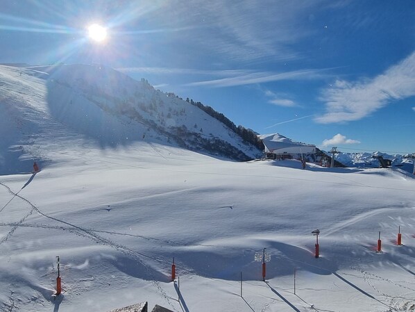 Une piste de ski enneigée, avec un ciel dégagé, des télésièges et une montagne en toile de fond.