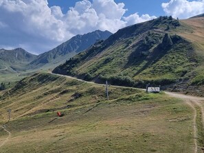 A mountainous landscape with a dirt road, a small building, and a utility pole.