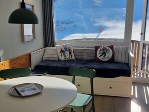 A cozy room with a sofa bed, a small table, and a window with a view of a snowy landscape.