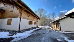A building with a sloped roof and wooden exterior walls. - Cozy T3 apartment near center with terrace and parking (Samoëns)