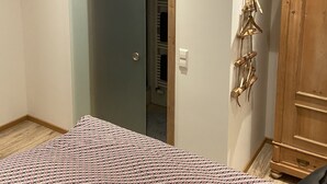 Un dormitorio con cama, armario y puerta que da a un baño.