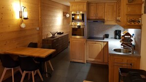 Eine kleine Küche mit Holzausstattung, einem eingebauten Backofen und einem Spülbecken.