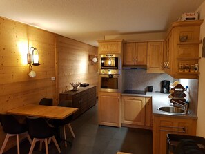 Eine kleine Küche mit Holzausstattung, einem eingebauten Backofen und einem Spülbecken.