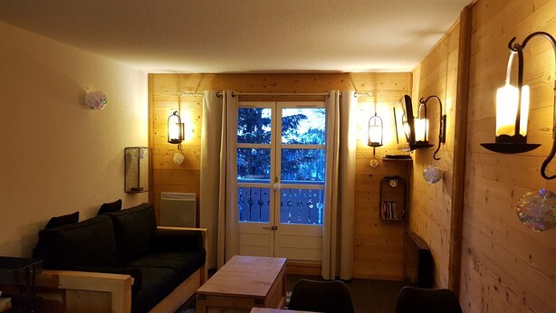 Ein gemütliches Zimmer mit Holzvertäfelung, einer Couch, einem kleinen Tisch und einem Fenster mit Vorhängen.