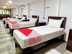 A hotel room with a bed, bedside table, and a window.