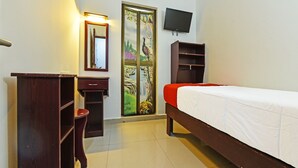 Un dormitorio con cama, escritorio, silla, armario, televisor y aire acondicionado.
