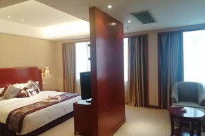 A hotel room with a bed, a TV, a wooden column, a chair, and a small table. - Daohuaxiang Hotel (Yichang)