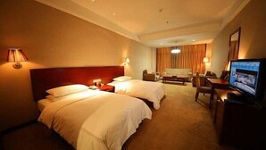 A hotel room with two beds, a desk, a chair, a television, and a lamp. - Daohuaxiang Hotel (Yichang)
