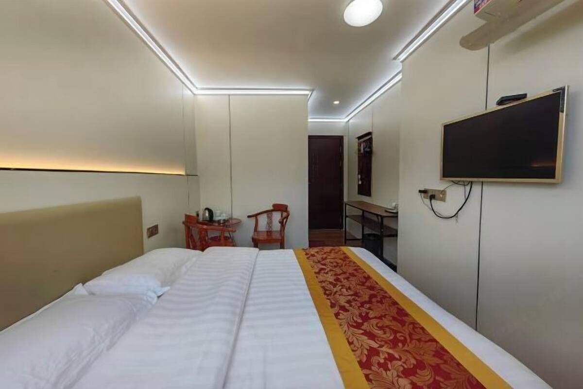 A hotel room with a bed, a desk, a chair, a television, and a wardrobe.