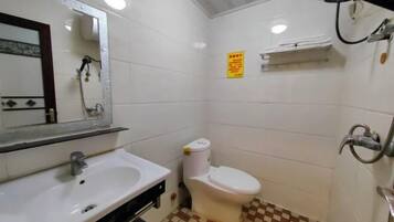 Een badkamer met een wit wastafelmeubel, toilet en douche.
