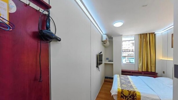 A hotel room with a bed, a red wardrobe, a desk, and a window with curtains. - Sanshenren Apartment (Shantou)