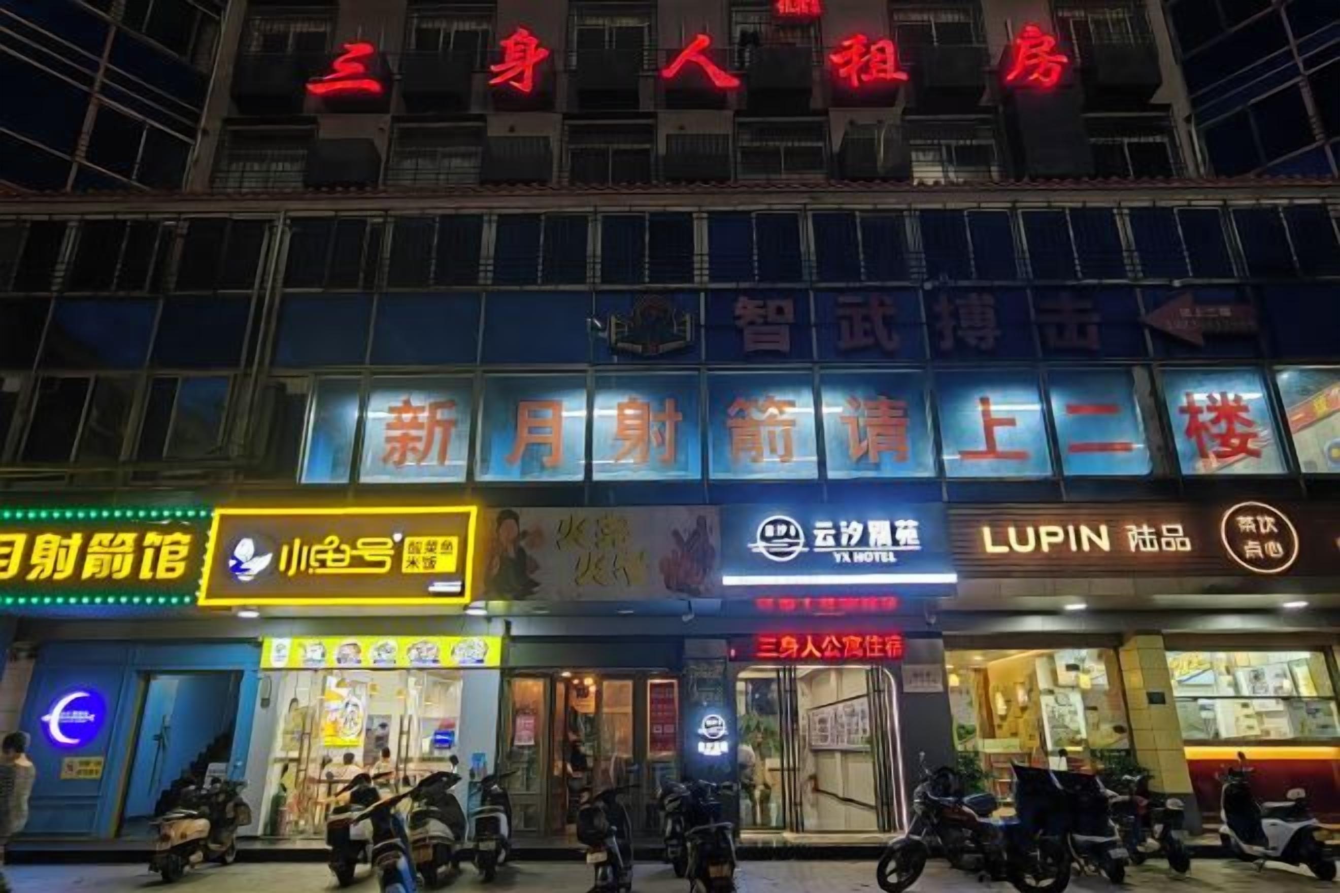A multi-story building with various commercial establishments on the ground floor, including a bank, a pharmacy, and a restaurant.