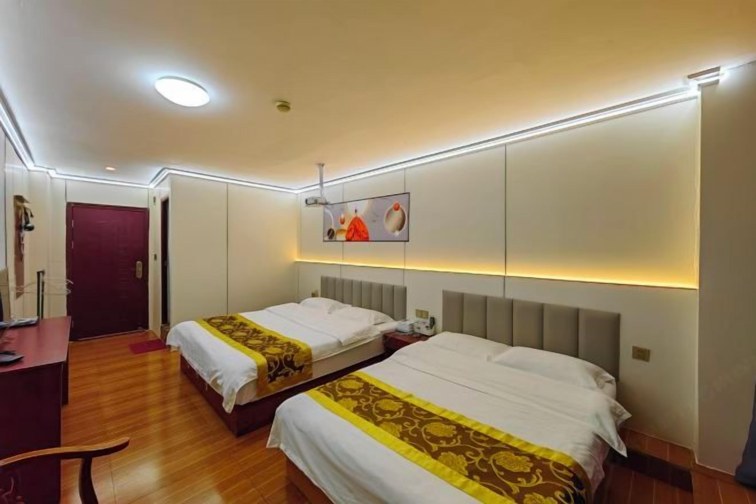 A hotel room with two beds, a desk, a chair, and a door.