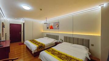 A hotel room with two beds, a desk, a chair, and a door.