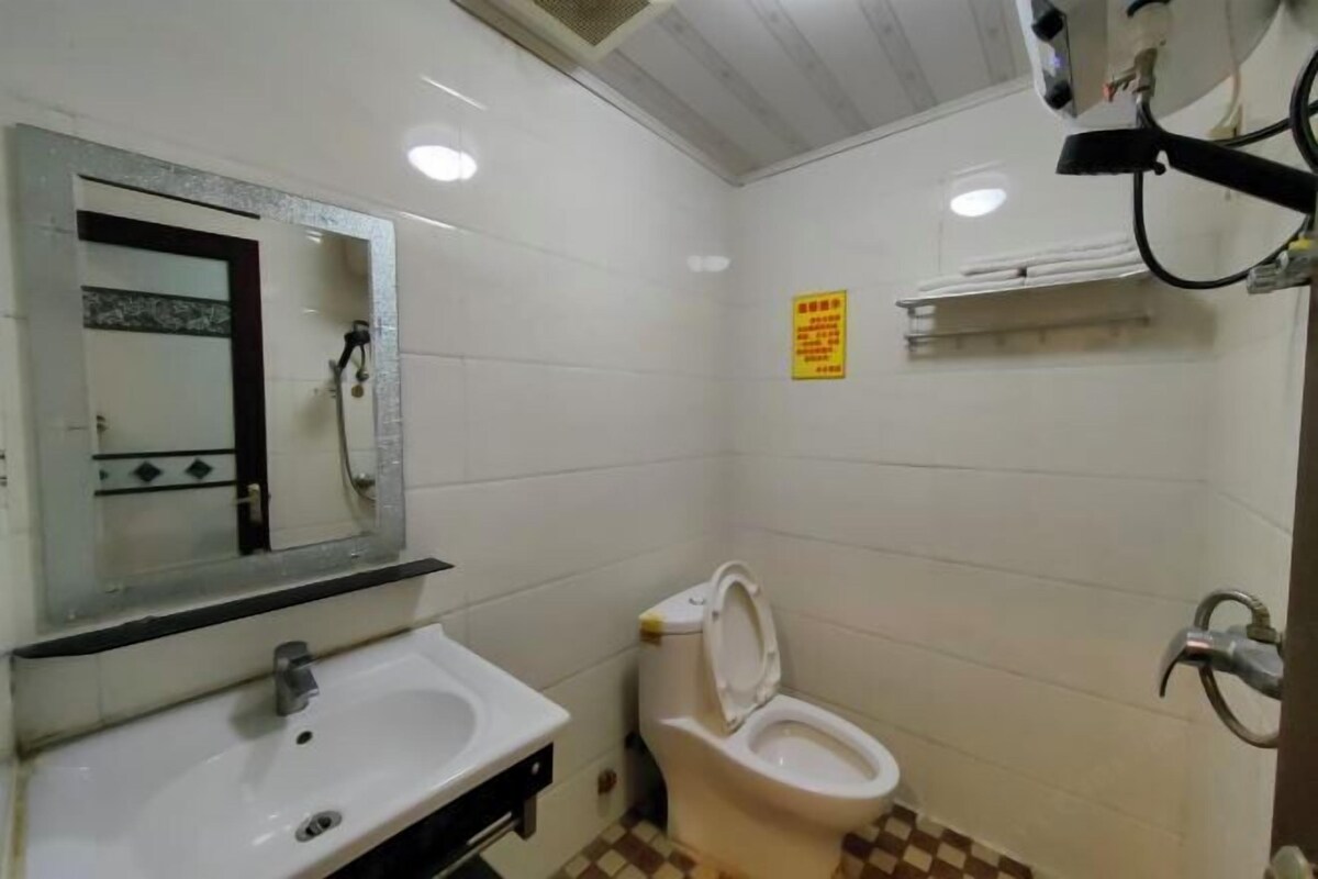 Un baño con un lavamanos blanco, un espejo, un inodoro y una zona de ducha.